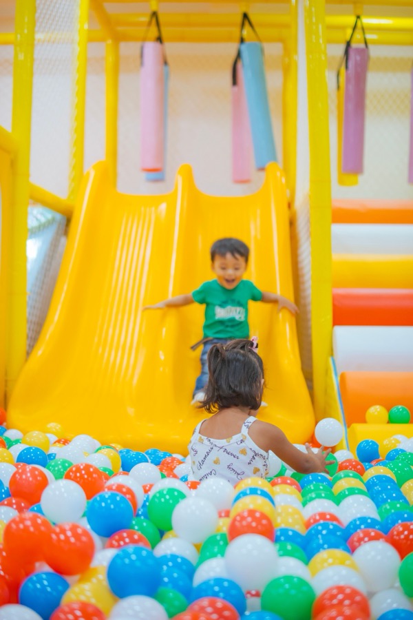Kids on a soft-play slide into a ball pit